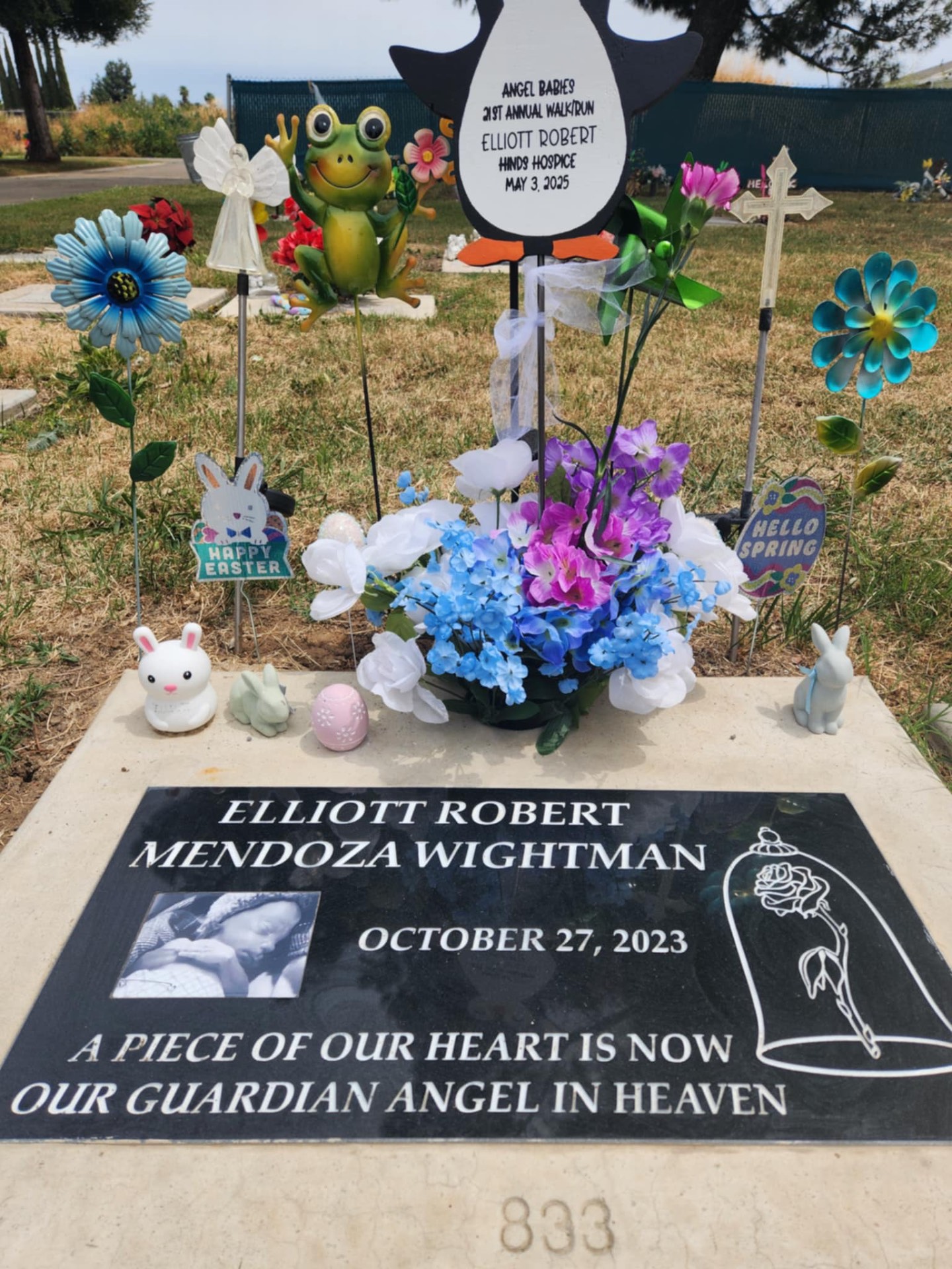 Elliott Robert Mendoza Wightman's headstone, surrounded by flowers and keepsakes left by his family